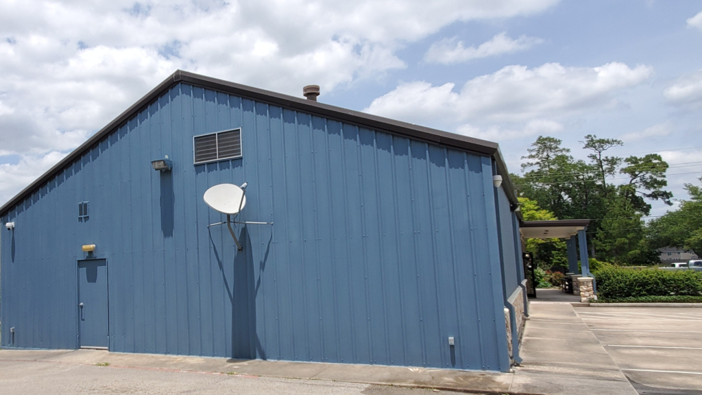 A blue building with a satellite dish on the roof against a clear sky.