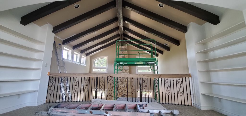 A room with a wooden ceiling and a ladder, leading to a hidden attic space.